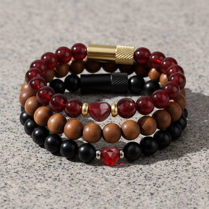 Black onyx beaded bracelet with red heart accent and silver waterproof pill holder on neutral stone background