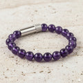 Purple beaded bracelet with a silver clasp on a white background