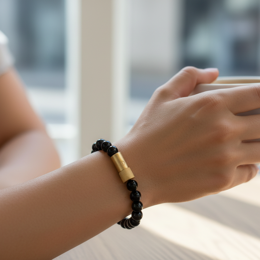 Black beaded bracelet with a gold pill holder on a white background