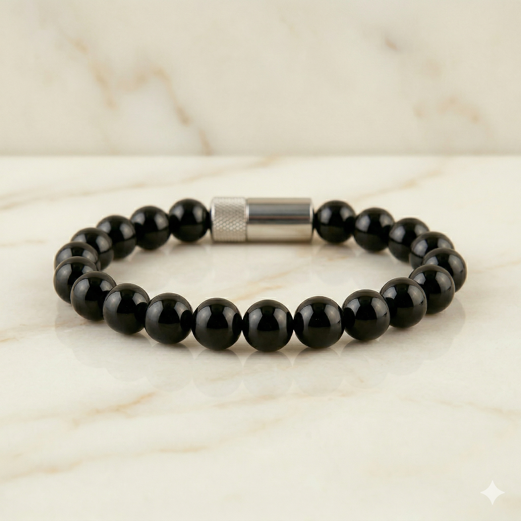 Black beaded bracelet with a silver clasp on a marble surface