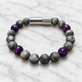 Matte gray Labradorite and purple Tiger’s Eye Embracelet™ with a discreet silver pill holder, displayed on white marble.