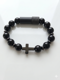 Black beaded bracelet with a cross charm on a white background