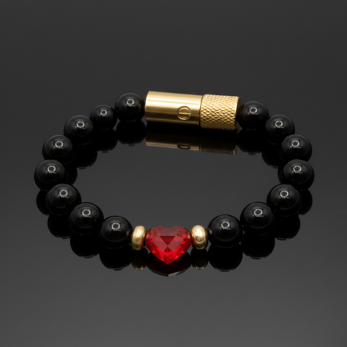 Black beaded bracelet with a red heart-shaped bead and gold clasp on a dark background