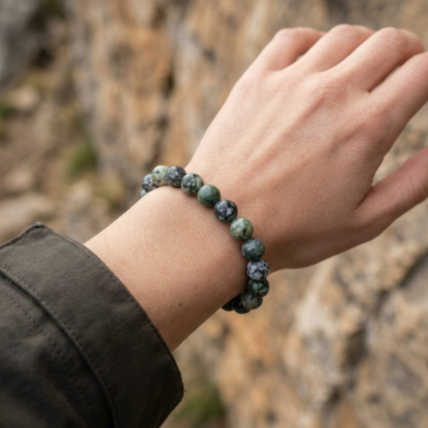 Hand wearing a beaded bracelet with a natural stone pattern against a blurred natural background pill holder bracelet
