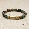 Beaded bracelet with a gold clasp on a textured surface